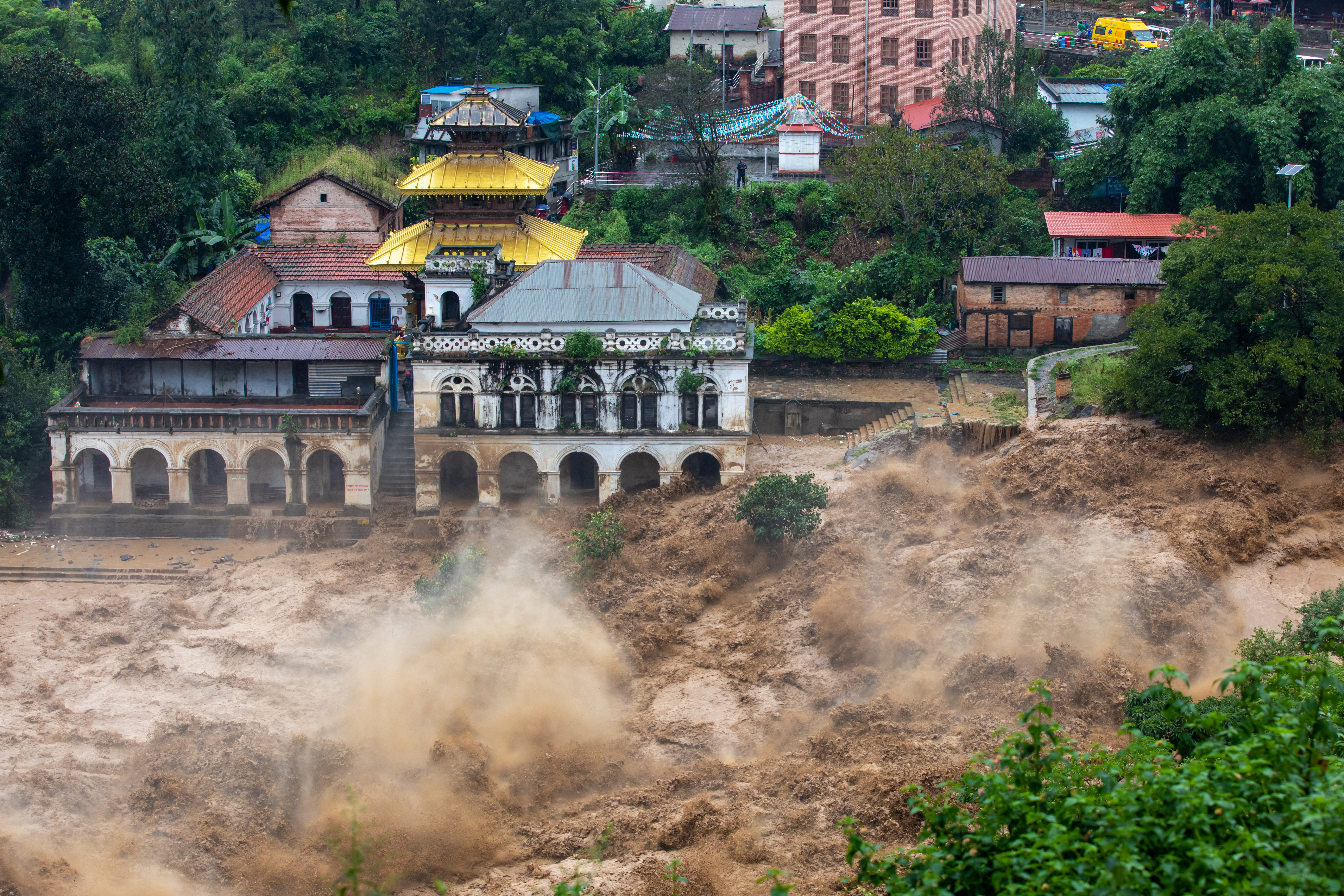 Flashflood rushing through a city and past damaged buildings..